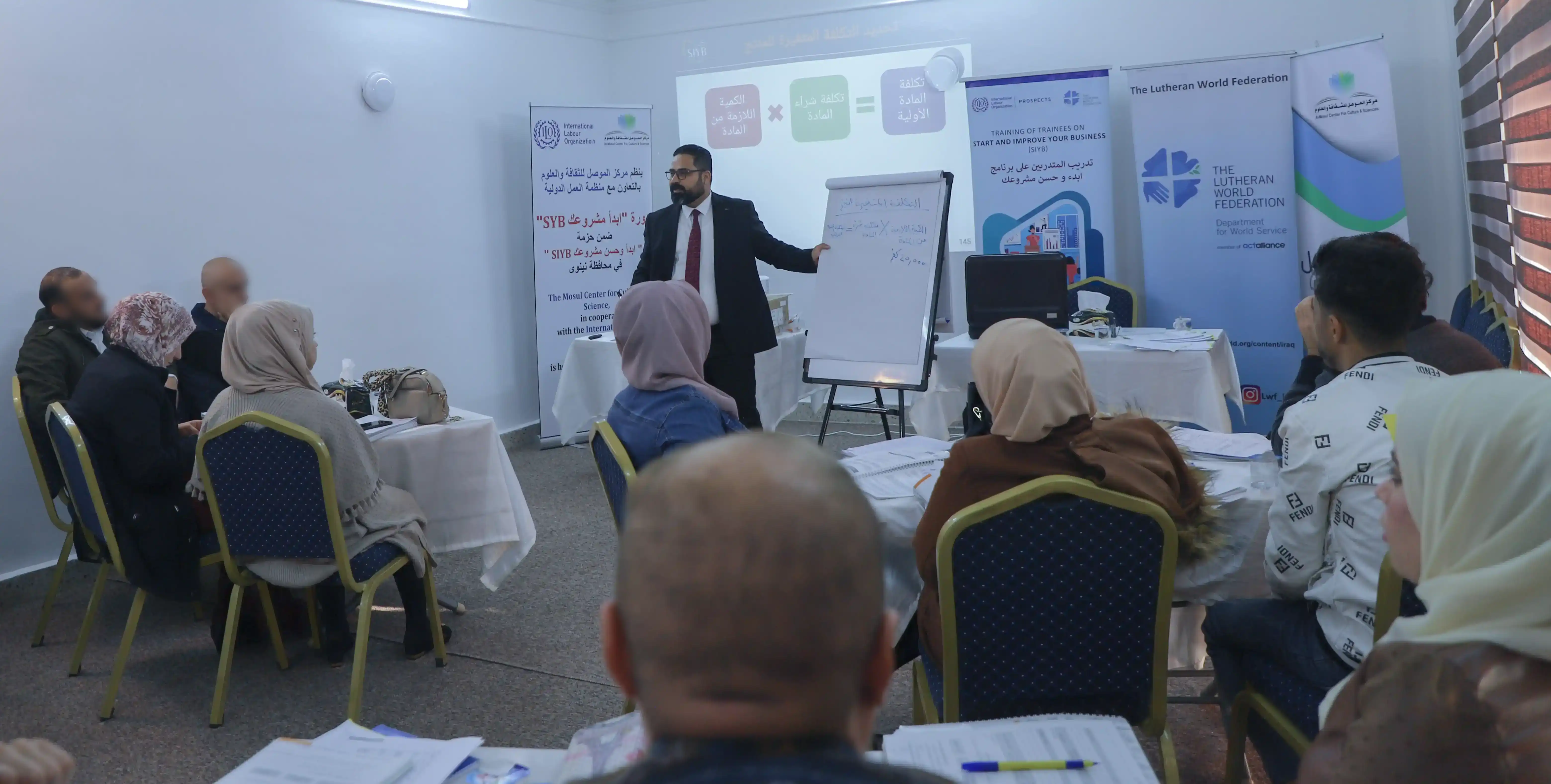 the president of the east gate center giving a course presentation 'Start your business SYIB' to a group of beneficiaries